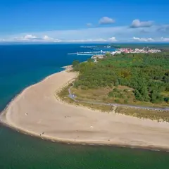 Spokojna plaża i las na Helu poza sezonem. W oddali widać miasteczko i port.