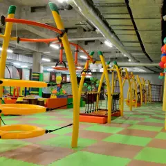Kolorowa, wielopoziomowa sala zabaw w **fun arena Gdańsk** z żółtymi konstrukcjami, huśtawkami i zieloną podłogą.