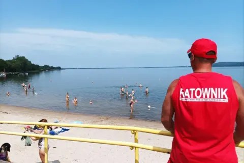 Ratownik czuwa nad bezpieczeństwem kąpiących się. Na plaży i w wodzie liczne atrakcje dla wypoczywających.