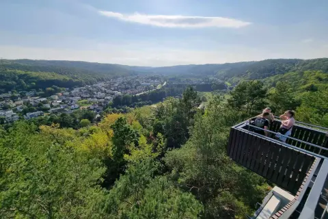 Widok z punktu widokowego w Rumi na zieloną dolinę i miasto. Kilka osób podziwia panoramę.