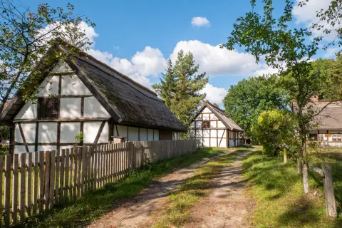 Tradycyjne chaty z drewnianą konstrukcją i strzechą, otoczone zielenią. Wspaniałe kluki atrakcje dla miłośników historii.
