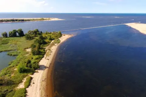Malowniczy deptak na wyspie Sobieszewskiej prowadzi przez wodę do piaszczystej ławicy.