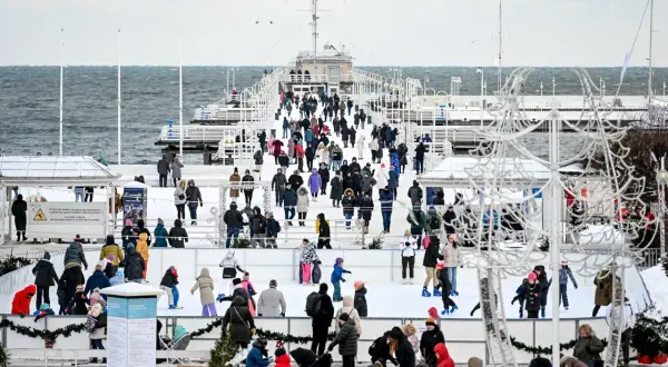 Sopot atrakcje zimą: lodowisko na molo, tłumy ludzi w ciepłych ubraniach, morze w tle.