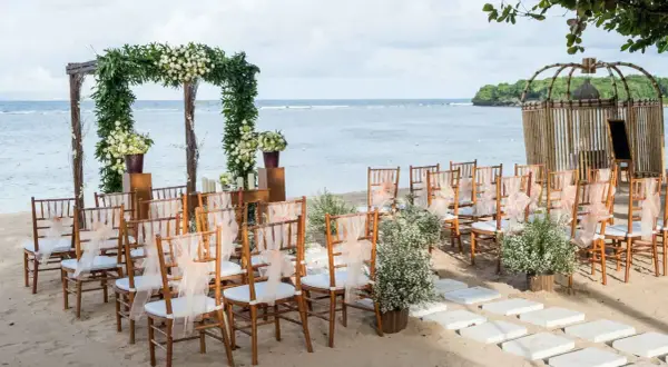 Ustawione krzesła i łuk z kwiatami czekają na ślub na plaży. Romantyczna sceneria nad morzem.