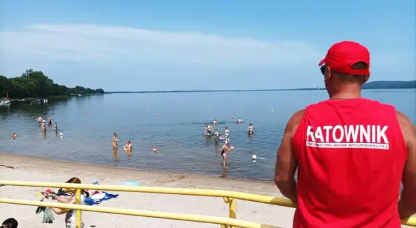 Ratownik czuwa nad bezpieczeństwem kąpiących się. Na plaży i w wodzie liczne atrakcje dla wypoczywających.