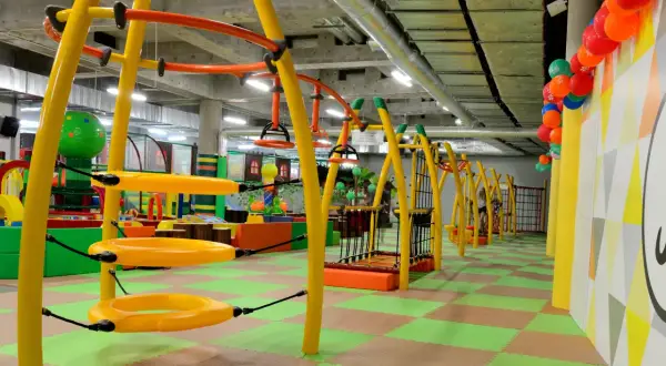 Kolorowa, wielopoziomowa sala zabaw w **fun arena Gdańsk** z żółtymi konstrukcjami, huśtawkami i zieloną podłogą.