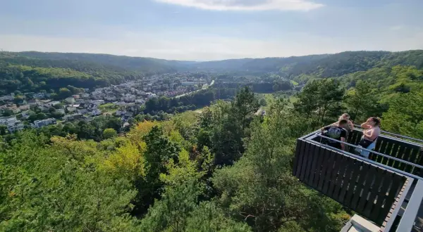 Widok z punktu widokowego w Rumi na zieloną dolinę i miasto. Kilka osób podziwia panoramę.