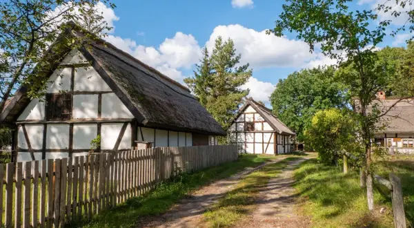 Tradycyjne chaty z drewnianą konstrukcją i strzechą, otoczone zielenią. Wspaniałe kluki atrakcje dla miłośników historii.