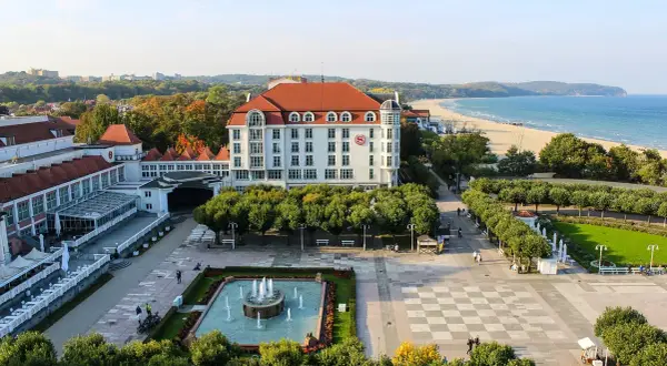 Spacerem po bulwarze nadmorskim, z widokiem na hotel, plażę i morze.