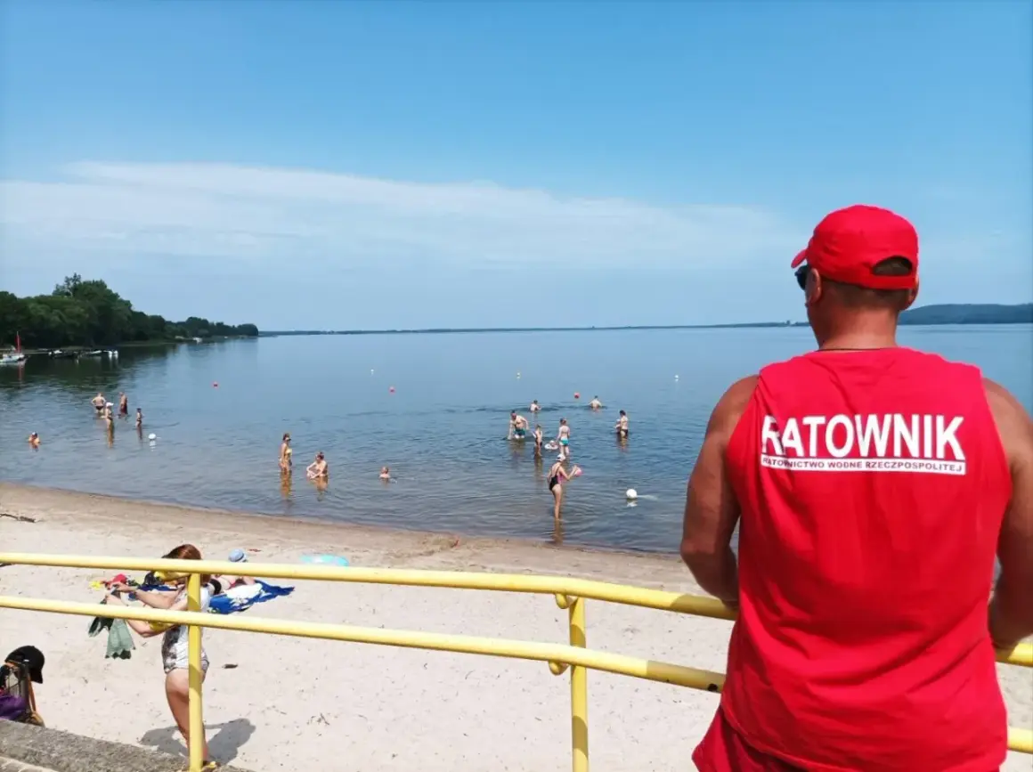 Ratownik czuwa nad bezpieczeństwem kąpiących się. Na plaży i w wodzie liczne atrakcje dla wypoczywających.