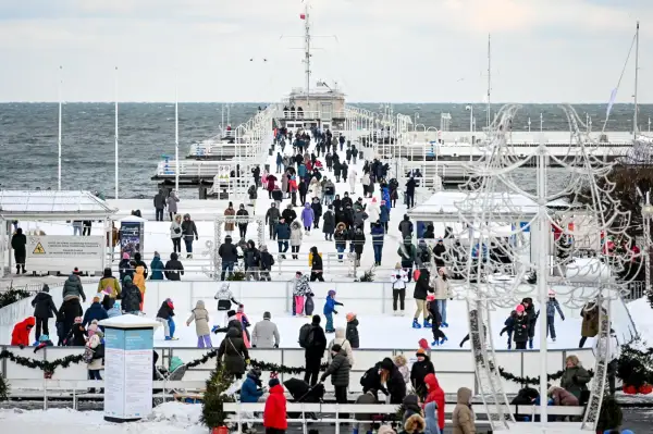 Sopot atrakcje zimą: lodowisko na molo, tłumy ludzi w ciepłych ubraniach, morze w tle.