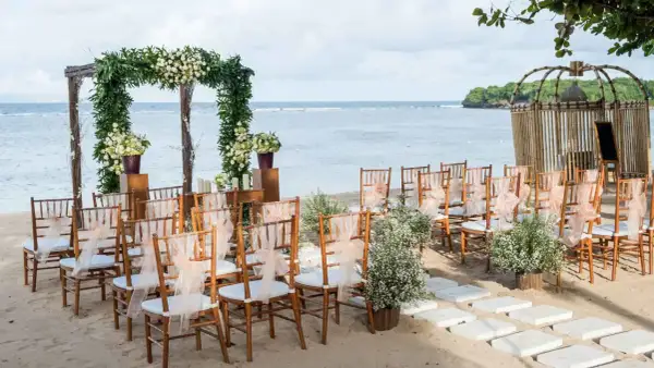 Ustawione krzesła i łuk z kwiatami czekają na ślub na plaży. Romantyczna sceneria nad morzem.