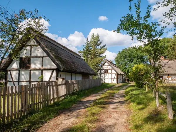 Tradycyjne chaty z drewnianą konstrukcją i strzechą, otoczone zielenią. Wspaniałe kluki atrakcje dla miłośników historii.